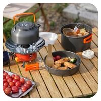 Outdoor cooking setup with pots, pans, and food on a wooden table.